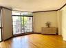 Sunlit living space featuring hardwood floors and oversized windows that fill the room with natural light. The open layout creates a comfortable setti