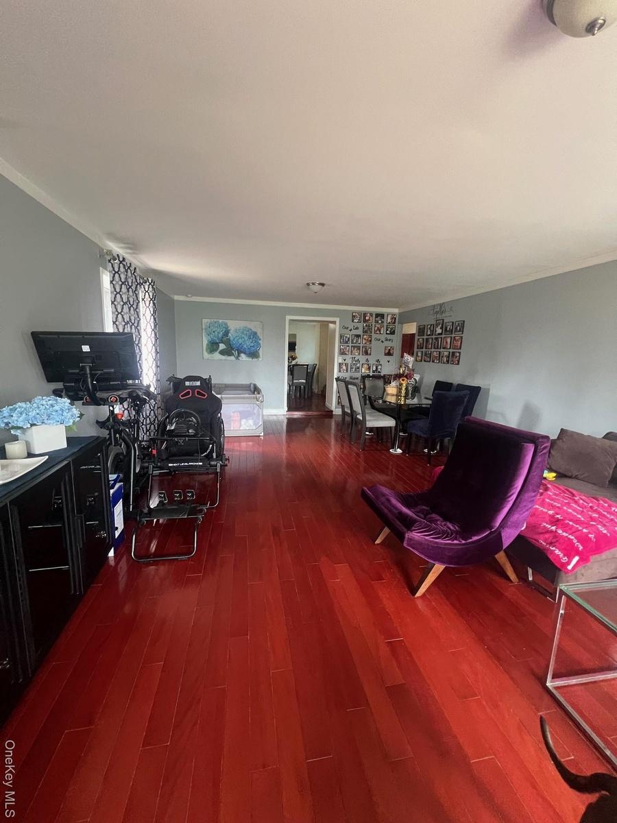 Living room with dark wood-type flooring and crown molding