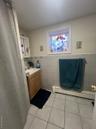 Bathroom with tile walls, light tile patterned floors, vanity, baseboard heating, and wainscoting