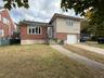 Split level home with brick siding, a garage, driveway, and a front yard