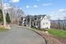 View of front of home with board and batten siding, driveway, stone siding, and a front lawn
