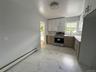 Kitchen featuring a baseboard heating unit, stainless steel electric stove, light marble finish flooring, decorative backsplash, and white cabinets