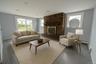 Living area with plenty of natural light, a brick fireplace, wood finished floors, a baseboard radiator, and recessed lighting