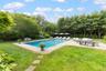 Outdoor pool with a patio area, a yard, view of scattered trees, and outdoor lounge area