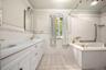 Full bath with tile walls, crown molding, double vanity, light tile patterned floors, and wainscoting