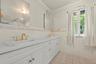 Full bath with light tile patterned floors, tile walls, ornamental molding, and double vanity