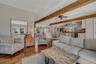 Living area featuring beamed ceiling, wood floors, and a ceiling fan