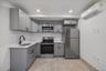 Kitchen with gray cabinetry, appliances with stainless steel finishes, light countertops, a wall mounted AC, and recessed lighting