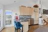 Kitchen with light brown cabinetry, dark wood-type flooring, a breakfast bar area, backsplash, and paneled fridge