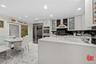 Kitchen with recessed lighting, fridge, light marble finish floors, light countertops, and glass insert cabinets