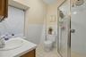 Full bathroom featuring vanity, tile walls, light tile patterned flooring, a shower stall, and a wainscoted wall