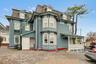Victorian home with mansard roof, a porch, and a high end roof