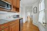 Kitchenette with a drop ceiling, stainless steel appliances, brown cabinetry, healthy amount of natural light, and light wood-style flooring