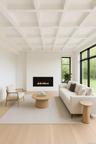 Living area featuring a warm lit fireplace, beamed ceiling, light wood-style floors, and coffered ceiling