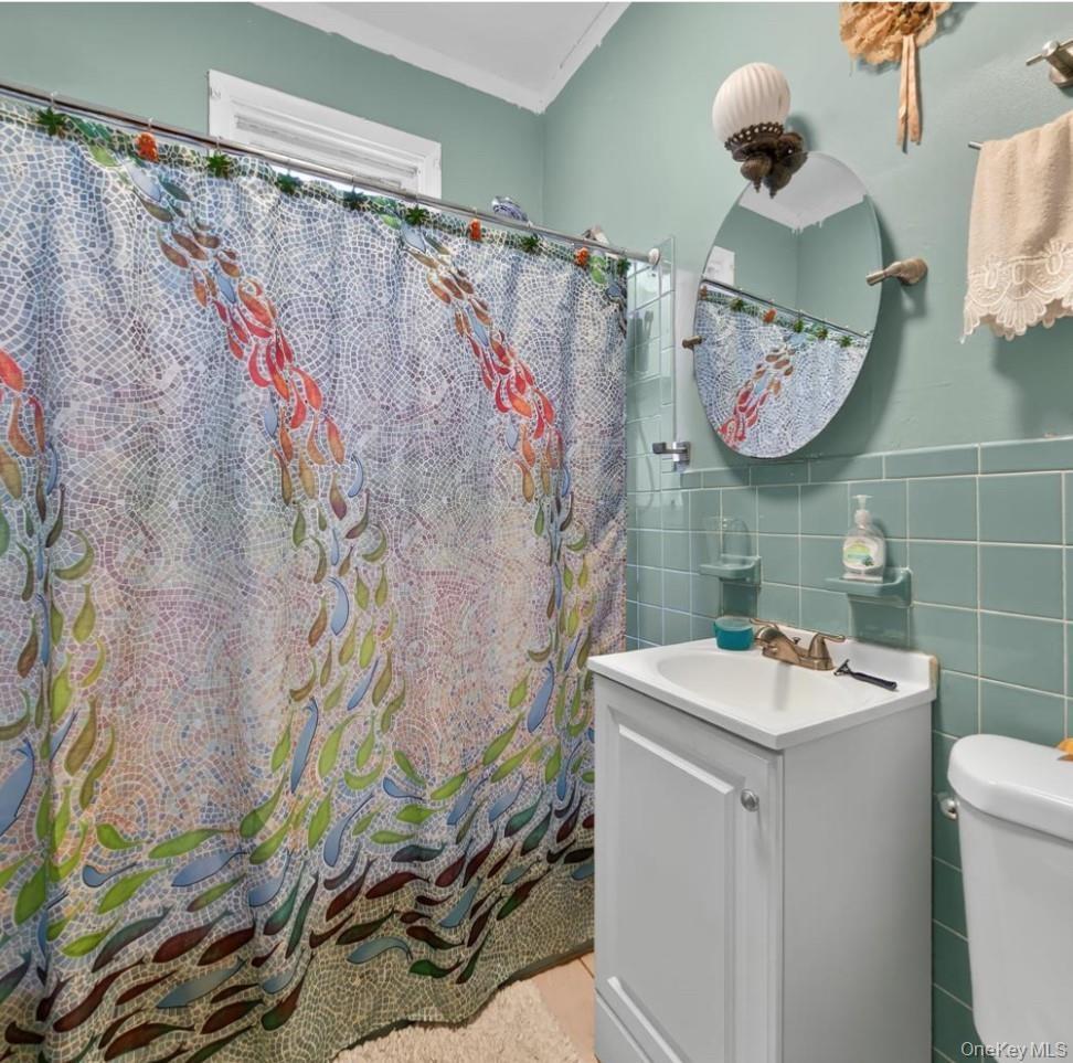 Bathroom with tile walls, vanity, crown molding, and a shower with shower curtain