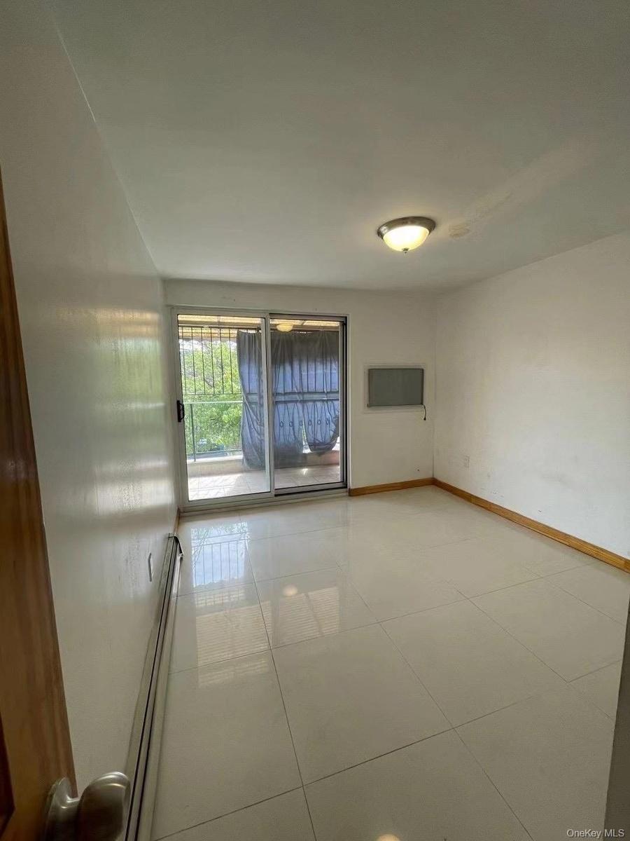 Unfurnished room featuring light tile patterned flooring and baseboard heating