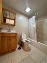 Bathroom with tile walls, shower / bath combo with shower curtain, vanity, and light tile patterned flooring