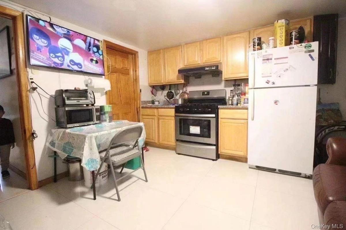 Kitchen with appliances with stainless steel finishes, light brown cabinets, under cabinet range hood, and light tile patterned floors