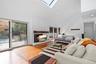 Living area with a skylight, light wood-type flooring, recessed lighting, high vaulted ceiling, and a lit fireplace