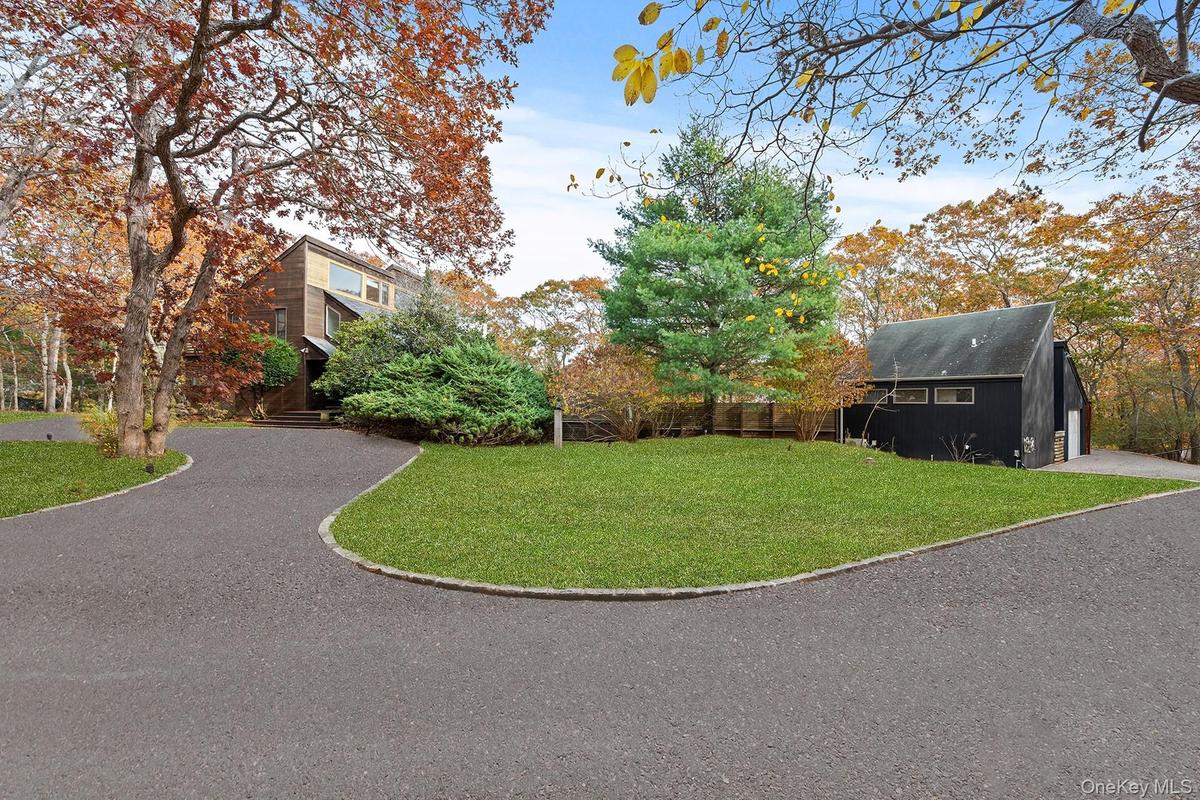 View of grassy yard with gravel driveway and an outdoor structure