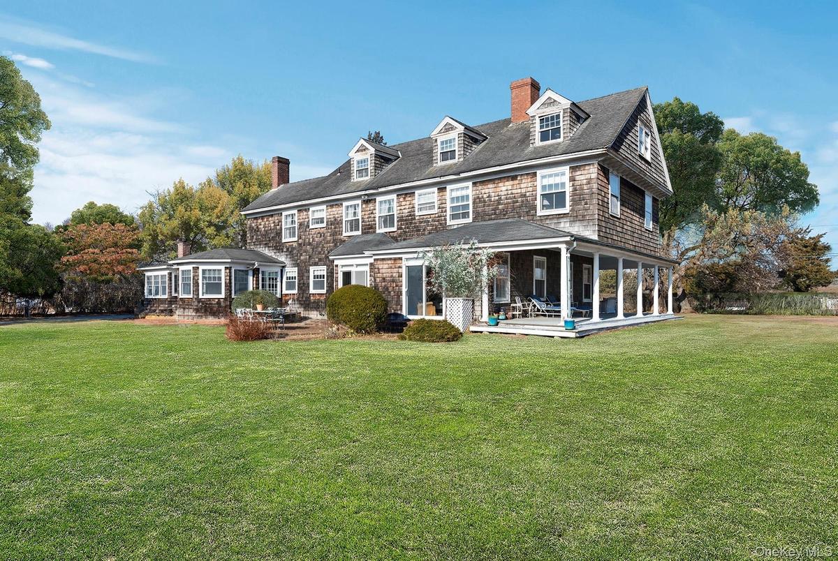 Rear view of property with expansive lawn, patio, and covered porch