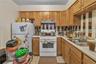 Kitchen featuring backsplash, white appliances, brown cabinets, light countertops, and a textured ceiling