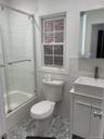 Bathroom with vanity, shower / bath combination with glass door, and tile walls