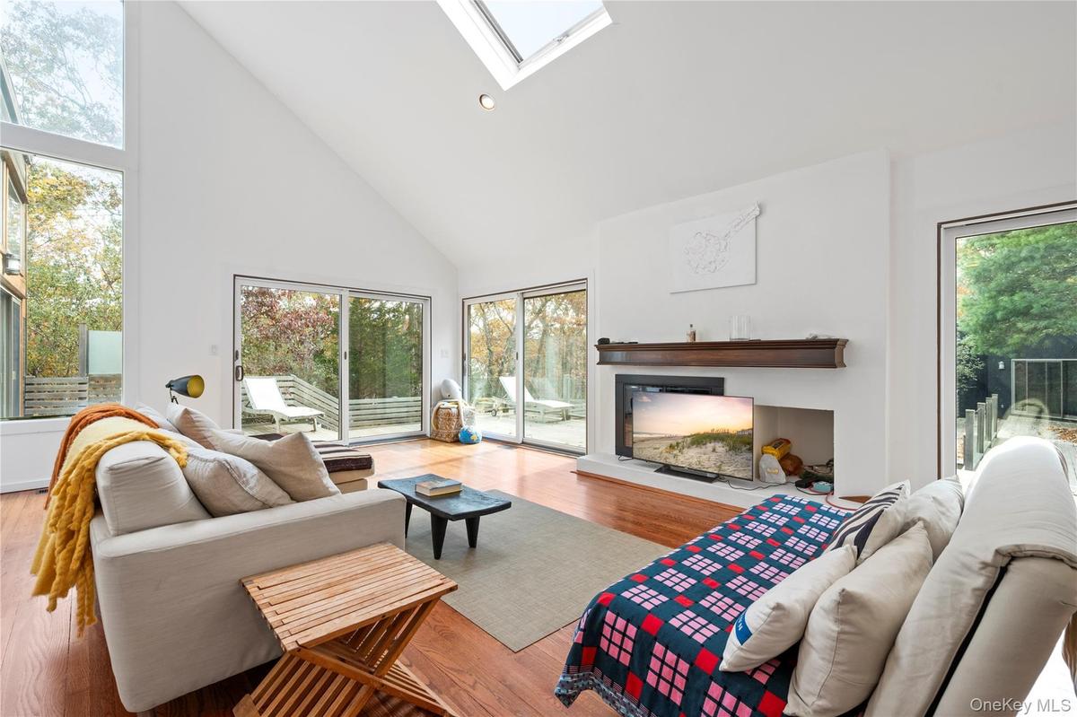 Living area featuring high vaulted ceiling, a skylight, light wood-style flooring, a glass covered fireplace, and recessed lighting