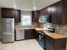 Kitchen with appliances with stainless steel finishes, dark brown cabinets, wooden counters, and recessed lighting