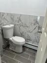 Bathroom featuring a baseboard heating unit, tile walls, wood tiled floors, and wainscoting