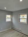Unfurnished room featuring a baseboard heating unit, recessed lighting, light wood-type flooring, and healthy amount of natural light