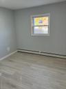 Unfurnished room featuring light wood-type flooring and baseboard heating
