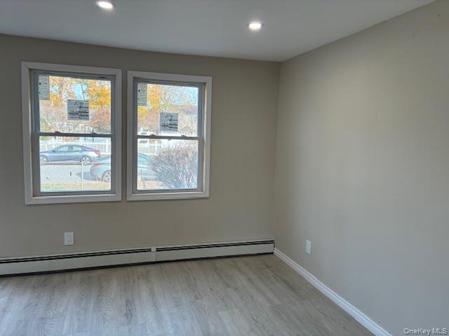 Unfurnished room featuring light wood-style flooring, a baseboard radiator, and recessed lighting