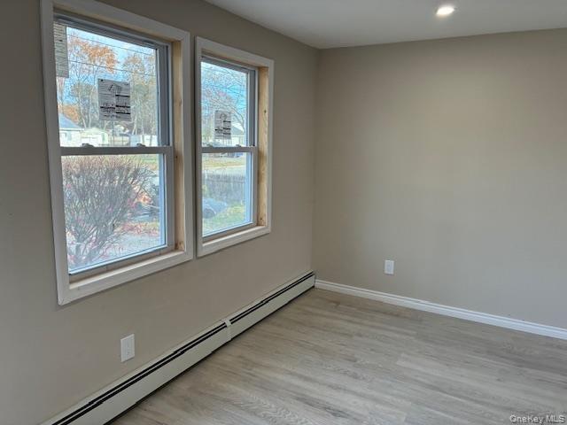 Spare room with a baseboard heating unit, light wood finished floors, and recessed lighting
