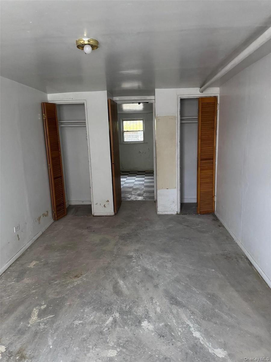 Unfurnished bedroom featuring multiple closets and concrete flooring