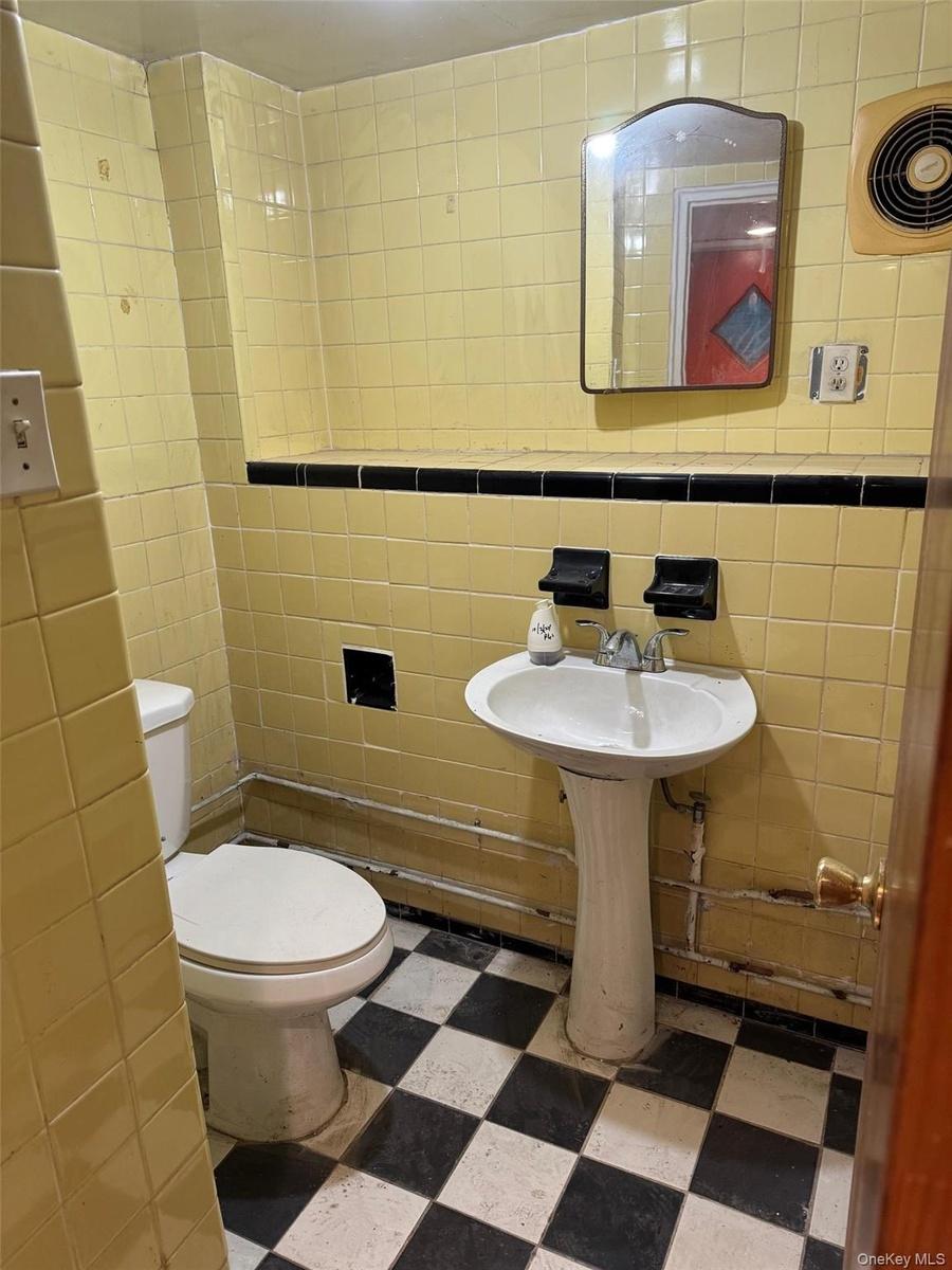Half bathroom with tile walls and dark floors