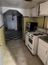 Kitchen with white range with gas cooktop, tile walls, white cabinetry, a wainscoted wall, and freestanding refrigerator