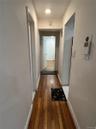 Hallway with dark wood-type flooring and baseboards