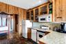 Kitchen featuring white appliances, tasteful backsplash, glass insert cabinets, stone tile floors, and wooden walls
