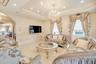 Living room featuring a chandelier, arched walkways, crown molding, a raised ceiling, and a decorative wall