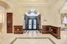 Foyer featuring arched walkways, inlaid floor details, crown molding, a wainscoted wall, and a decorative wall