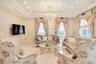 Living area featuring a decorative wall, crown molding, a wainscoted wall, a raised ceiling, and a chandelier