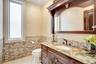 Bathroom with vanity, tile walls, light tile patterned floors, a wainscoted wall, and ornamental molding