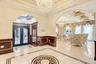 Foyer entrance with inlaid floor details, a chandelier, arched walkways, ornamental molding, and light tile patterned floors