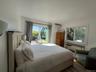 Bedroom featuring multiple windows and a wall mounted air conditioner
