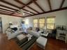Living area featuring beamed ceiling, dark wood-type flooring, plenty of natural light, ceiling fan, and a decorative wall