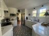 Kitchen with white cabinetry, appliances with stainless steel finishes, premium range hood, light stone counters, and wood ceiling