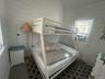 Bedroom with wooden walls, lofted ceiling, and cooling unit