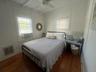 Bedroom featuring dark wood-style flooring, beam ceiling, ceiling fan, and cooling unit