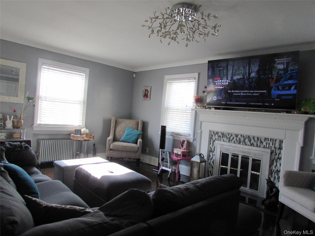 Living room with radiator heating unit, a fireplace, and crown molding